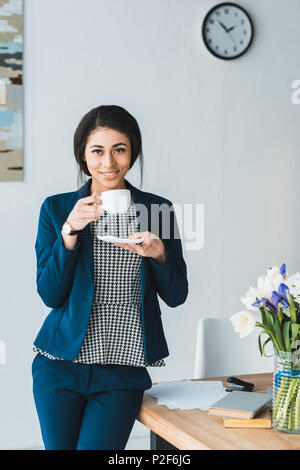 Female manager enjoying coffee in modern office Banque D'Images