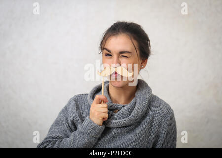 Belle jeune fille avec une moustache sur un bâton en bois,vêtu d'un chandail tricoté confortable Banque D'Images