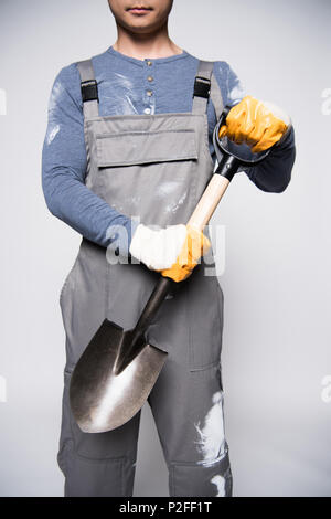 Cropped shot of young construction worker dans des combinaisons et des gants de sécurité tenant une petite pelle. Banque D'Images