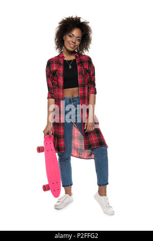 Cheerful young african american woman posing with skateboard and smiling at camera isolated on white Banque D'Images