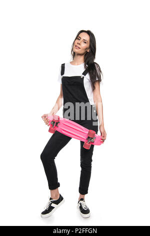Belle jeune femme holding skateboard and looking at camera isolated on white Banque D'Images