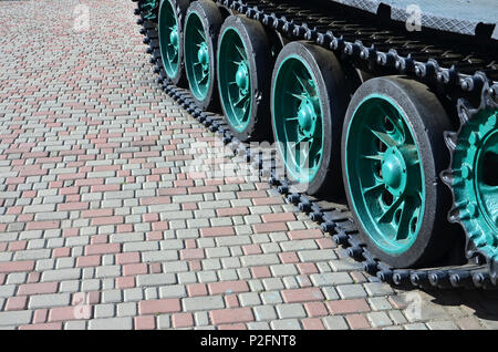 Un véhicule militaire sur chenilles se tient sur un carré de pavés. Photo de chenilles vertes avec des roues en métal que les faire tourner Banque D'Images