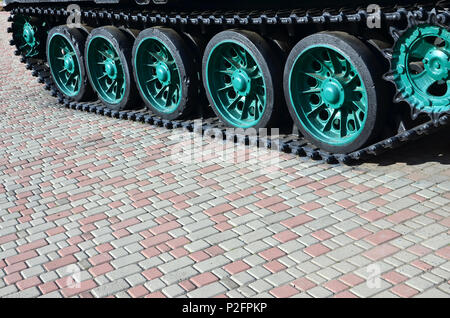 Un véhicule militaire sur chenilles se tient sur un carré de pavés. Photo de chenilles vertes avec des roues en métal que les faire tourner Banque D'Images