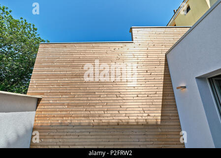 Mur de ciment blanc rénové et d'isolation de bardage bois dans une cour Banque D'Images