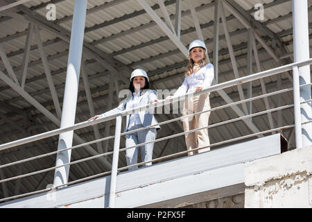 Les architectes dans l'usure formelle looking at camera while standing at construction site Banque D'Images