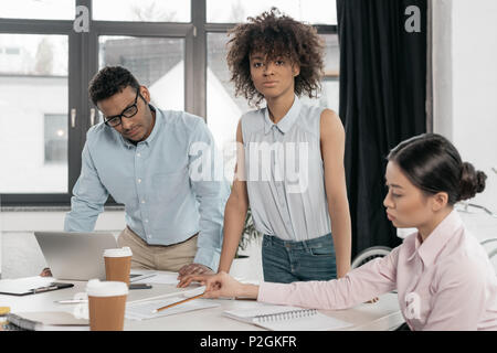 Groupe de jeunes gens d'affaires multiethniques doing paperwork at office Banque D'Images