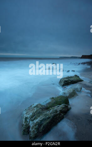 Une belle et de l'atmosphère de Seascape quelques roches sur la plage ou littoral sur l'île de Wight. Lumière froide bleu mystérieux sur le rivage soir Banque D'Images