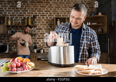 L'homme souriant dans la préparation tout en lunettes toasts homme barbu pouring coffee derrière Banque D'Images
