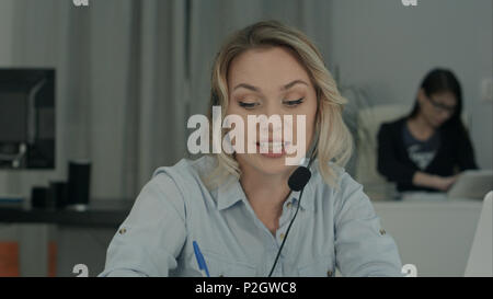 Jeune femme manager en discussion d'affaires ayant casque via ordinateur portable Banque D'Images