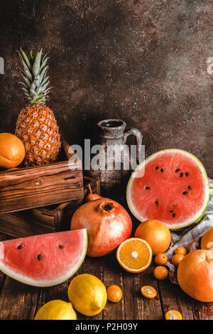 Des oranges, des tranches de pastèque, grenades, ananas et kumquats sur table en bois rustique Banque D'Images