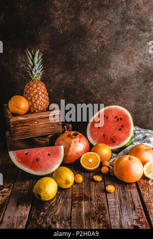 Tranches de melon d'eau, oranges, grenades, ananas et kumquats sur table en bois rustique Banque D'Images