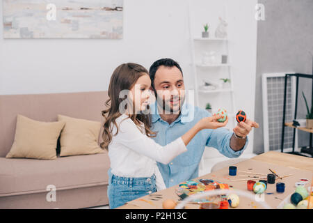 Le père et sa fille à la recherche des oeufs de pâques fraîchement peint à Banque D'Images