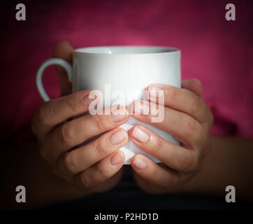 Les mains tiennent une tasse blanche Banque D'Images