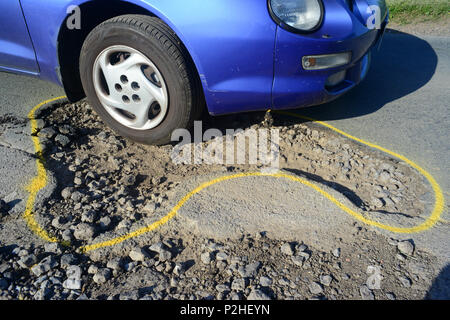 Location d'une conduite sur un énorme pot hole sur route marquée avec contour jaune pour la réparation,york yorkshire unitedc-uni Banque D'Images