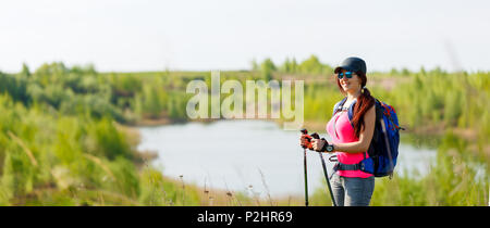 Photo panoramique de la femme sportive avec les bâtons de marche sur fond de lac et de la végétation verte Banque D'Images