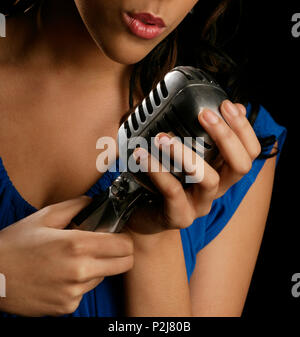 Young woman singing into a microphone de style rétro Banque D'Images