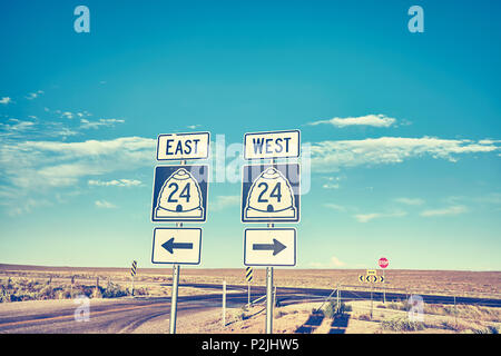 Est ou Ouest, retro photo aux couleurs de la signalisation routière au coucher du soleil, le choix et le concept de voyage. Banque D'Images
