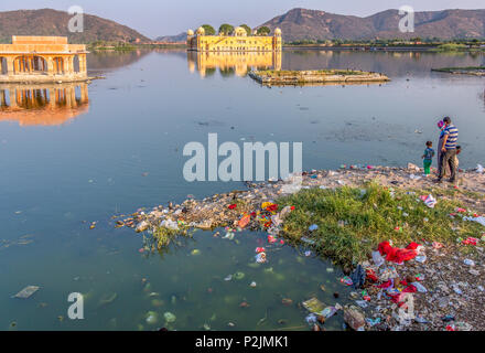 Une famille debout sur la rive de la polluée Man Sagar Lake en regardant le Jal Mahal Palace, une attraction touristique à Jaipur, Inde. Banque D'Images