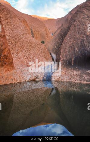 Reflet de la roche le long de la base d'Uluru au lever du soleil Banque D'Images