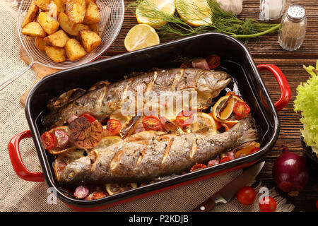 Poisson frais cuit avec légumes et pommes de terre dans le moule, sur fond de bois Banque D'Images