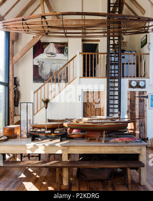 Salle à manger avec double hauteur 1940 fire modèle échelle et coques de navires avec de vieux châssis en canot dans le Sussex grange convertie Banque D'Images