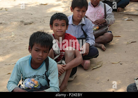 Des écoliers s'asseoir en ligne sur l'aire de sable de rame École rurale au Cambodge. Banque D'Images