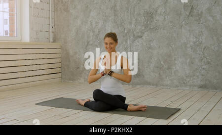 Portrait of beautiful smiling young woman working out à l'intérieur dans l'intérieur loft faire Marichyasana posent avec geste namaste Banque D'Images