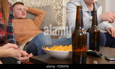 Groupe d'amis assis sur le canapé, regarder la télévision ensemble et boire de la bière Banque D'Images