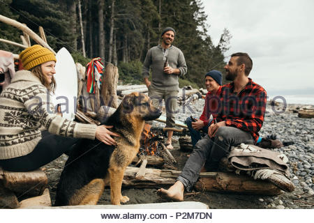 Amis avec chien bénéficiant d'escapade week-end surf, détente au camping sur la plage de robuste