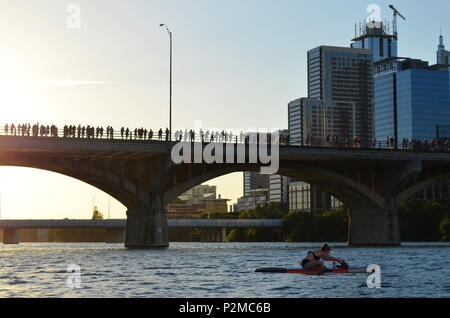 Une femme s'étend sur un paddle board tout en flottant sur le lac Ladybird comme une foule se rassemble pour regarder les chauves-souris apparaissent. Congrès Ave Banque D'Images