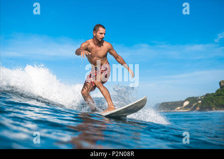 Bel homme sportif s'amusant sur une planche de surf aux beaux jours pendant les vacances d'été Banque D'Images