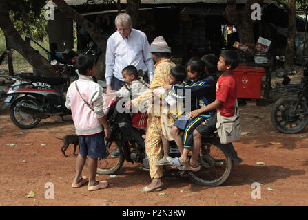 Une moto avec six personnes sur il prend les enfants de l'école. M. Conor Gilligan, l'un des collecteurs de fonds, les regarde. Rame à l'école, au Cambodge. Banque D'Images