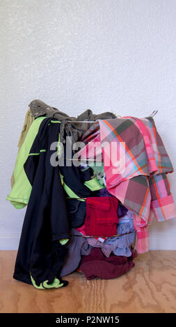 Panier à linge en métal sans un sac plein, avec des vêtements sales contre mur blanc, fond sur plancher en bois Banque D'Images