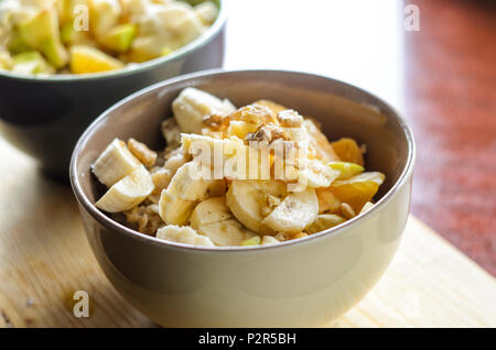 Petit-déjeuner sain Bol : avoine avec de la banane, de l'orange, vert pomme, noix, graines de sésame et Chia Banque D'Images