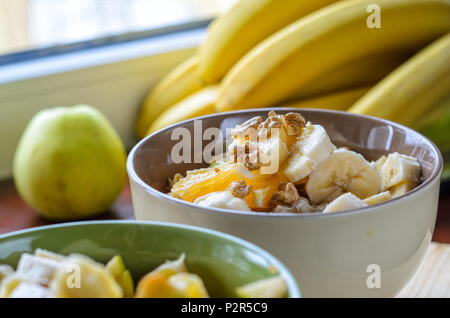 Petit-déjeuner sain Bol : avoine avec de la banane, de l'orange, vert pomme, noix, graines de sésame et Chia Banque D'Images