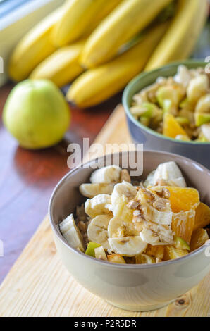 Petit-déjeuner sain Bol : avoine avec de la banane, de l'orange, vert pomme, noix, graines de sésame et Chia Banque D'Images