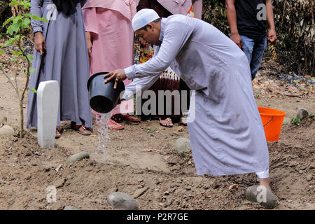 Lhokseumawe, Indonésie. 16 Juin, 2018. Un musulman vu tomber l'eau sur un des parents tombe au cours du pèlerinage.musulmans vu de leurs proches tombe, lors d'un pèlerinage au cimetière public à Lhokseumawe Ville. La plupart des musulmans à Aceh déjà fait le dernier pèlerinage grave avant d'entrer dans le mois sacré du Ramadan et le jour de l'Aïd al-Fitr, à prier pour les familles de ceux qui sont morts. Credit : Maskur a/SOPA Images/ZUMA/Alamy Fil Live News Banque D'Images