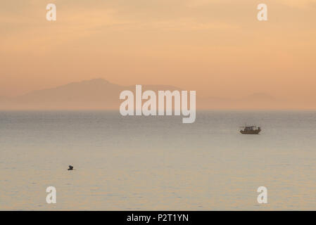 Bateau solitaire et un héron voler au coucher du soleil, Barra de Guaratiba. Rio de Janeiro, Brésil. Banque D'Images