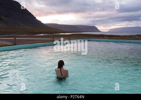 L'Islande, Fjords de l'Ouest, Bildudalur, Reykjarfjordur, femme dans une piscine géothermique au bas de fjord Arnarfjordur Banque D'Images