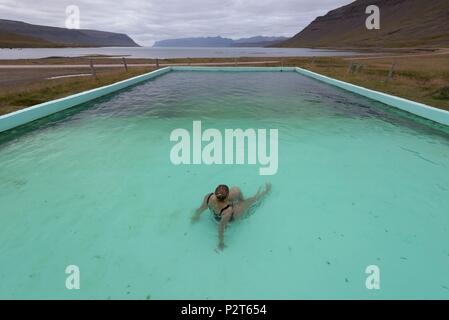 L'Islande, Fjords de l'Ouest, Bildudalur, Reykjarfjordur, femme dans une piscine géothermique au bas de fjord Arnarfjörður Banque D'Images