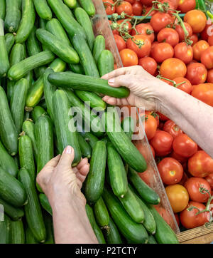Part d'une femme âgée picking green concombres dans un magasin Banque D'Images