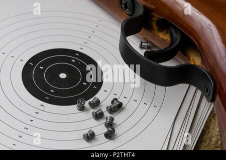 Arme de tir et pneumatique. Bouclier et hits avec balles de plomb sur une table en bois. Fond sombre. Banque D'Images