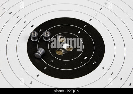 Arme de tir et pneumatique. Bouclier et hits avec balles de plomb sur une table en bois. Fond sombre. Banque D'Images