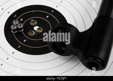 Arme de tir et pneumatique. Bouclier et hits avec balles de plomb sur une table en bois. Fond sombre. Banque D'Images