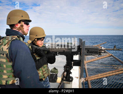 Océan (jan. 23, 2014) l'Aviation maître de Manœuvre (fossiles) Airman Kirk Ramos, droite, tire une mitrailleuse de calibre .50 alors que l'Artilleur 4400 2e classe Justin Blennis observe à bord du navire quai de transport amphibie USS New York (LPD 21). ( Banque D'Images