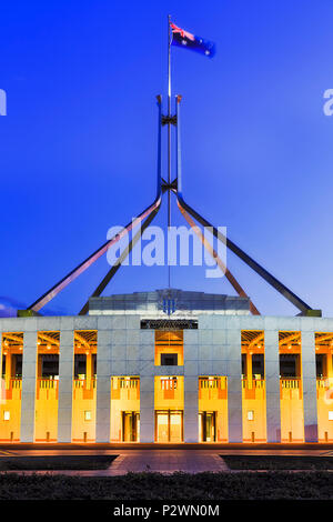 Drapeau australien national sur un mât au-dessus de l'édifice du gouvernement - la maison du parlement à Canberra sur la colline du Capitole au coucher du soleil avec l'éclairement du capteur pour lumineux Banque D'Images