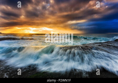 Moody seascape lever de soleil sur l'horizon de l'océan Pacifique au large de la plage de Bungan sur Sydney plages du nord pendant une tempête. Banque D'Images