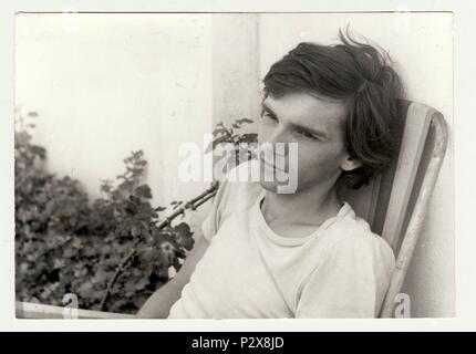 LA RÉPUBLIQUE SOCIALISTE TCHÉCOSLOVAQUE - JUILLET 1981: Une photo d'époque montre un adolescent assis sur une chaise de camping à l'extérieur.Photographie rétro en noir et blanc. Jeune Banque D'Images
