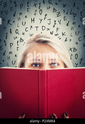 Close up portrait of pretty student girl se cacher derrière un livre ouvert rouge avec relative lettres alphabet sur l'arrière-plan. Femme timide et mystérieux garder Banque D'Images