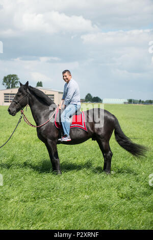 Le sergent-chef de l'US Air Force. Luis Rodriguez, avec le 86e Escadron de préparation logistique rides Soubirac, un enfant de 11 ans cheval Frison administré par le sergent. Yvonne Greco comme aviateurs américains avec le 424e Escadron de la base de l'air et de leurs familles, de la famille et de la sécurité en fête retour à l'école journée sur la base aérienne de Chièvres, dans la région de Chièvres, Belgique, Août 09, 2016. (U.S. Photo de l'armée par Visual Spécialiste de l'information, Pierre-Etienne Courtejoie) Banque D'Images